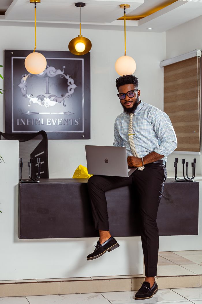Confident young man in a stylish office, using a laptop and smiling.